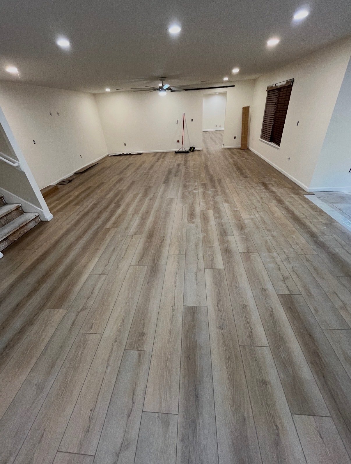 Finished flooring in an open living room with staircase